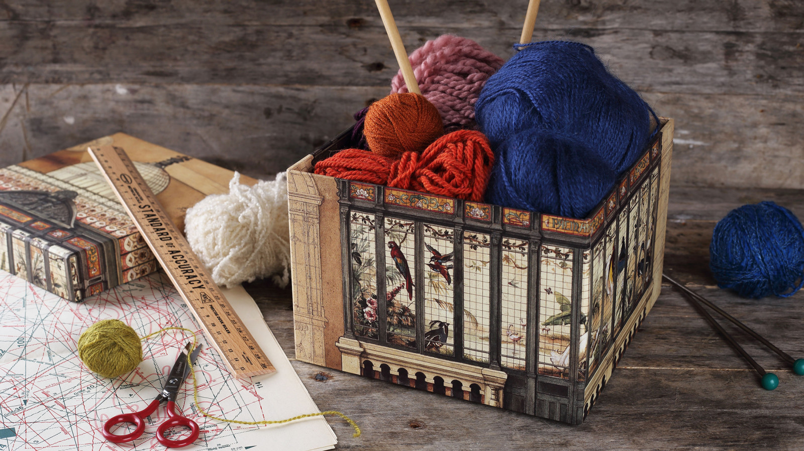 Craft table with a decorative box, yarn, scissors, and vintage papers