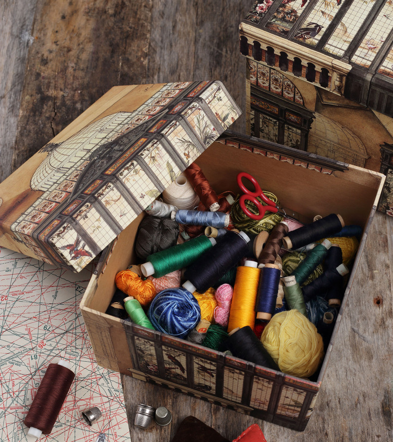 Vintage paper box filled with colorful thread spools and craft supplies